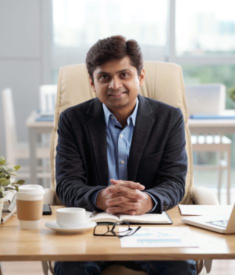 Confident smiling CEO of company sitting at his office table